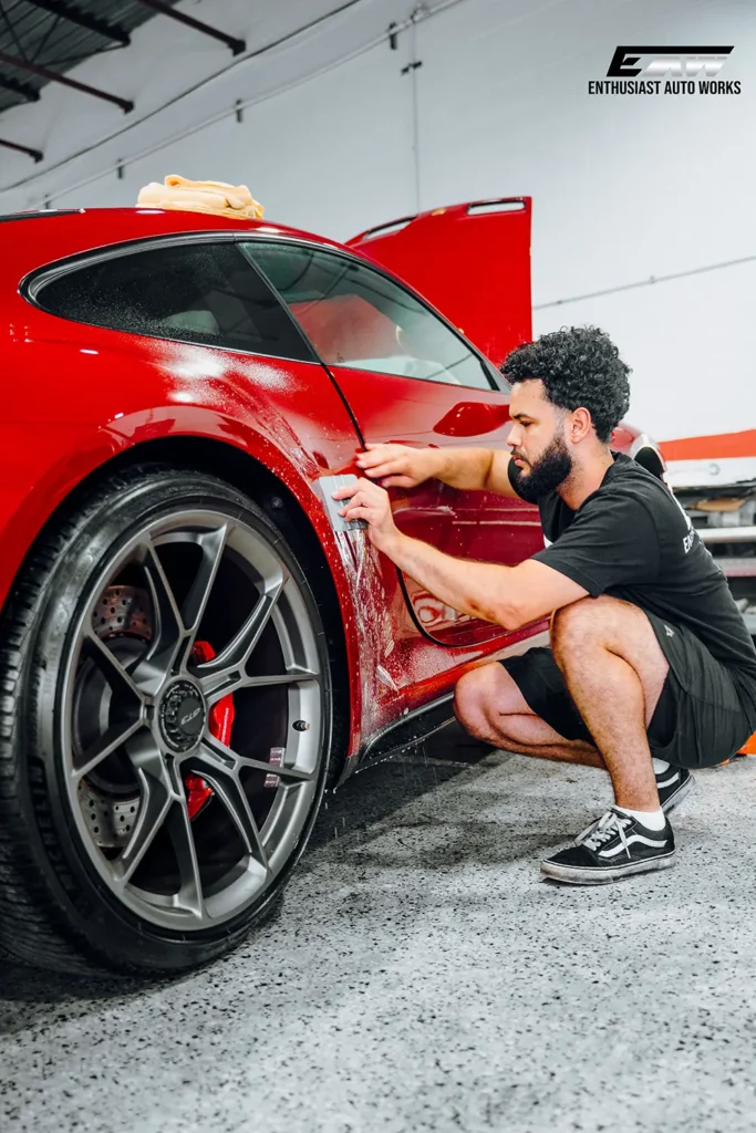 Technician applying XPEL paint protection film by hand at Enthusiast Auto Works